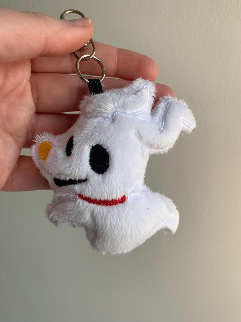 Puede incluir: Llavero de peluche blanco de Zero de The Nightmare Before Christmas. El llavero presenta el dise&ntilde;o del perro fantasma de Zero con ojos negros, un collar rojo y una nariz amarilla. Est&aacute; unido a un anillo de metal plateado.