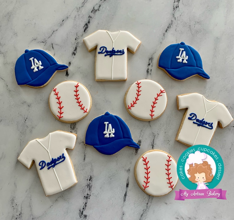 Pu&ograve; includere: Un set di nove biscotti decorati a tema baseball e Los Angeles Dodgers. I biscotti sono decorati con glassa blu, bianca e rossa. I biscotti includono palline da baseball, maglie da baseball e cappellini da baseball.