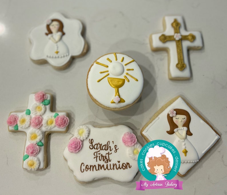 May include: Set of six decorated sugar cookies for a First Communion celebration. The cookies feature a cross with pink flowers, a chalice with a host, a girl in a white dress, and a banner that reads "Sarah's First Communion".