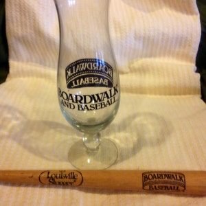 May include: A clear glass with a black and white logo that says "Boardwalk and Baseball" and a wooden baseball bat with the text "The Louisville Slugger" and "Boardwalk Baseball".