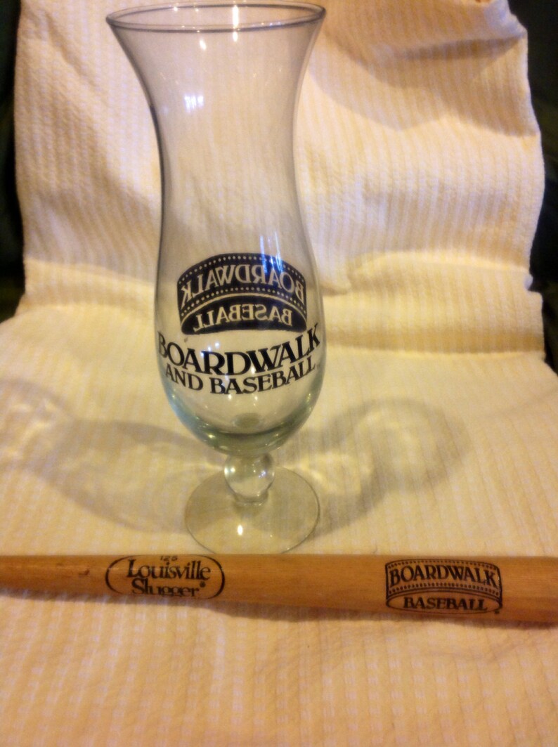 May include: A clear glass with a black and white logo that says "Boardwalk and Baseball" and a wooden baseball bat with the text "The Louisville Slugger" and "Boardwalk Baseball".