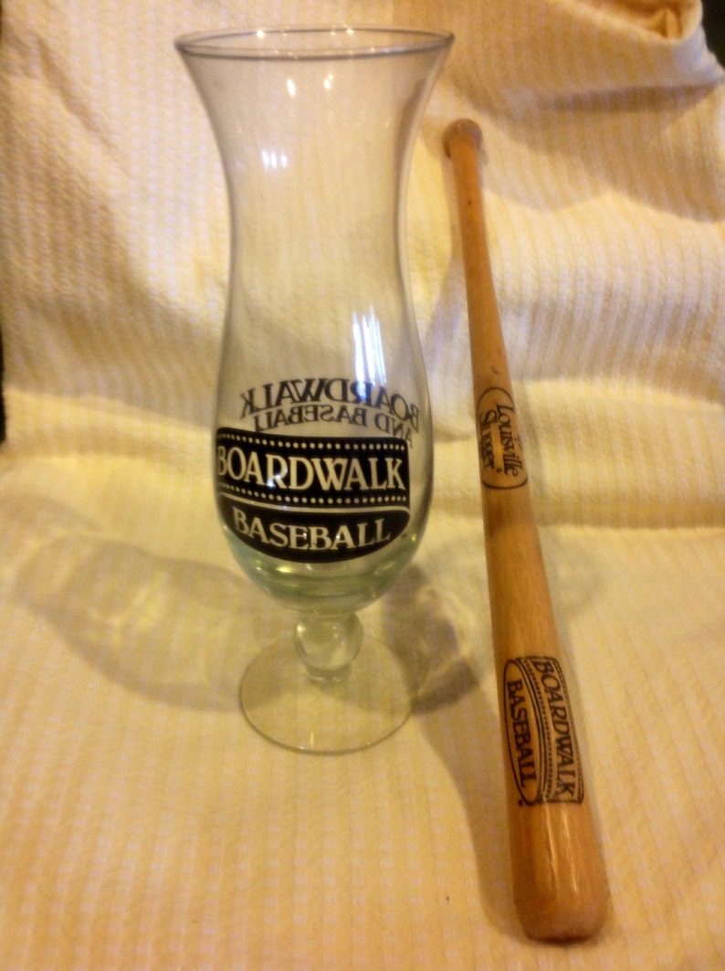 May include: A clear glass with a black and white logo that says "Boardwalk Baseball" and a wooden baseball bat with a black and white logo that says "Boardwalk Baseball".