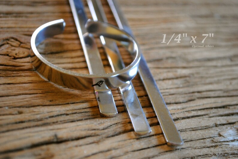 May include: A silver metal bracelet with a bird design. The bracelet is 1/4 inch wide and 7 inches long. The bracelet is on a wooden surface.