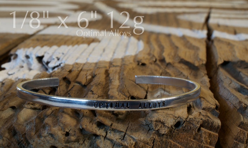 May include: A silver bracelet with the words "Optimal Alloys" engraved on it. The bracelet is 1/8 inch wide and 6 inches long and weighs 12 grams.