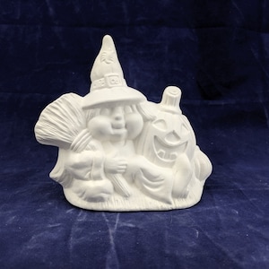 May include: White ceramic figurine of a witch holding a broom and a pumpkin with a carved face. The witch is wearing a hat with a pointed top and a buckle.