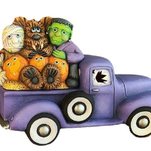 May include: A purple vintage pickup truck with a broken window.  Three Halloween characters are riding in the bed of the truck: a mummy, a werewolf, and Frankenstein's monster.  The truck is decorated with pumpkins.
