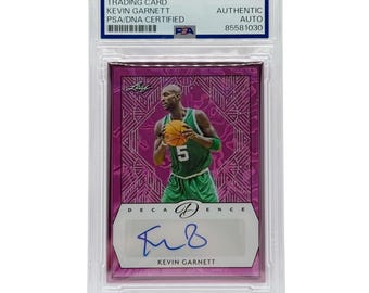 May include: A Kevin Garnett trading card in a protective case. The card features an image of Garnett in a green and white basketball uniform, holding a basketball. The card is signed and labeled "AUTHENTIC AUTO".