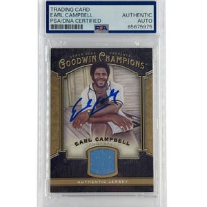 May include: A trading card of Earl Campbell, PSA/DNA certified, in a protective case. The card features a photo of Campbell, an autograph, and a blue jersey swatch. The card is from the Goodwin Champions series.