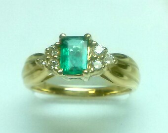 May include: A gold ring with a green emerald gemstone and small diamonds set in the band.