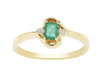May include: A gold ring with a green emerald gemstone and two smaller diamonds. The ring has a twisted band.