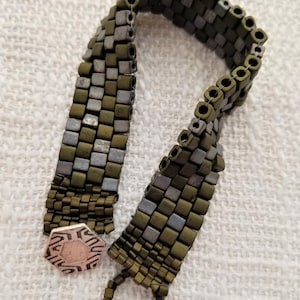 May include: A green and silver beaded bracelet with a silver hexagonal clasp and a silver ring closure.