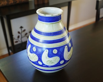 May include: A white ceramic vase with blue and green stripes and stylized bird designs.