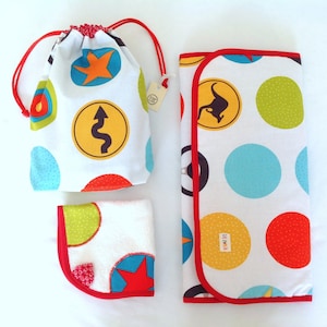 May include: A set of three baby items in a white background. The items are a white drawstring bag with colorful circles and stars, a white burp cloth with colorful circles and a kangaroo, and a white bib with colorful circles and a star.
