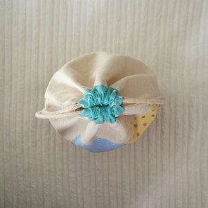 May include: A white canvas drawstring bag with a blue and white polka dot drawstring closure. The bag has a yellow and purple design on the bottom.