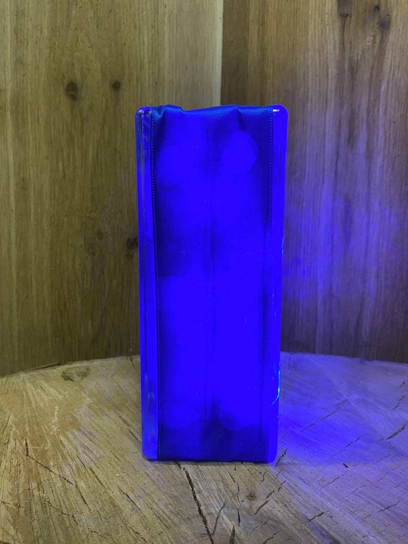 May include: A blue glass block with a smooth, polished surface. The block is illuminated from within, creating a bright blue glow.