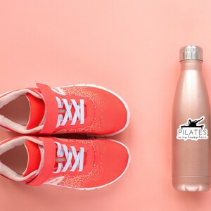 May include: A pair of red athletic shoes with white laces and a pink background. A rose gold water bottle with a black sticker that says "PILATES is my happy hour" is on the right side of the image.