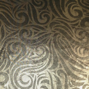 May include: A gold fabric with a black swirl pattern.