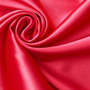May include: A close-up of a vibrant red satin fabric, draped and folded to create a soft, swirling pattern. The fabric is smooth and luxurious, with a subtle sheen.