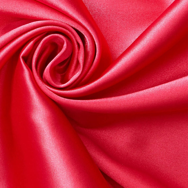 May include: A close-up of a vibrant red satin fabric, draped and folded to create a soft, swirling pattern. The fabric is smooth and luxurious, with a subtle sheen.