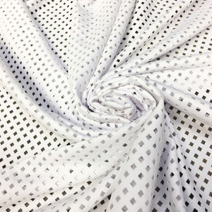 May include: White fabric with a square-shaped cut-out pattern. The fabric is folded and draped.