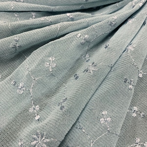 May include: Pale blue tulle fabric with a delicate white floral embroidery pattern.