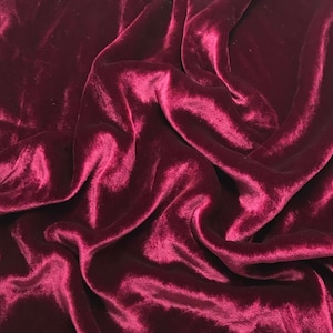 May include: Close-up of a deep red velvet fabric with soft, flowing folds and a luxurious texture.