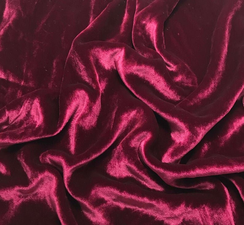 May include: Close-up of a deep red velvet fabric with soft, flowing folds and a luxurious texture.