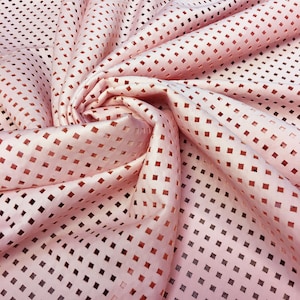May include: Pink fabric with a square pattern cut-out design. The fabric is soft and has a delicate texture.