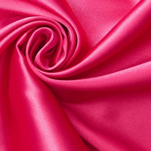May include: A close-up of a vibrant pink satin fabric, draped and folded to create a soft, swirling pattern.