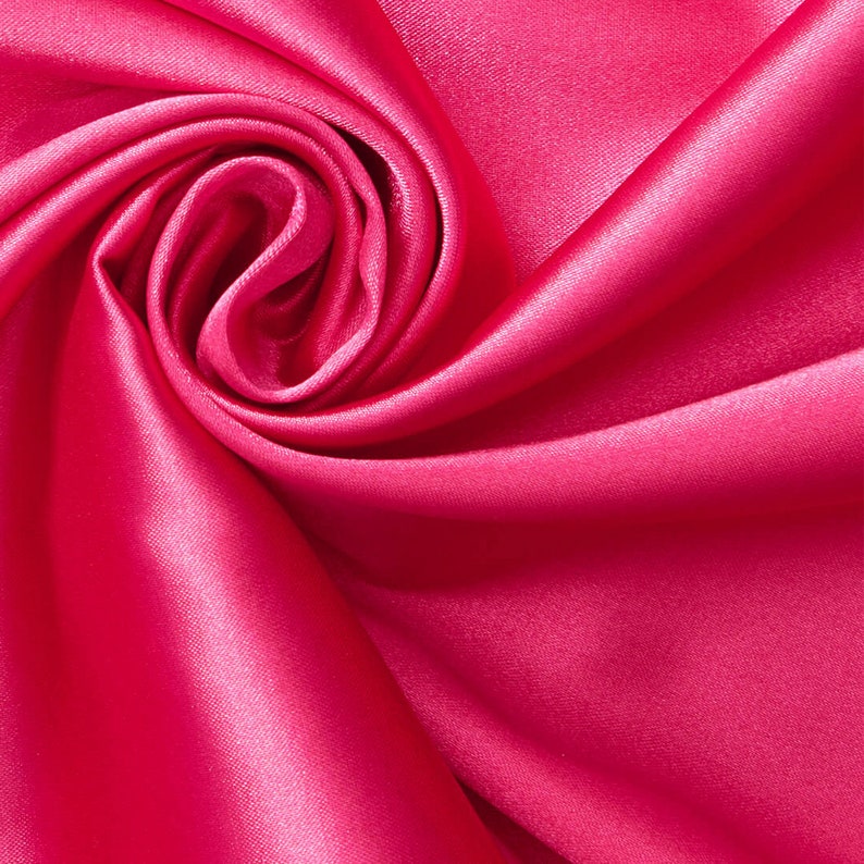May include: A close-up of a vibrant pink satin fabric, draped and folded to create a soft, swirling pattern.