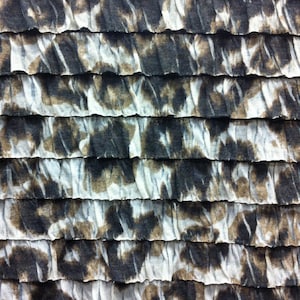 Peut inclure: Gros plan sur un tissu &agrave; texture pliss&eacute;e. Le tissu est blanc avec des motifs abstraits bruns et noirs.