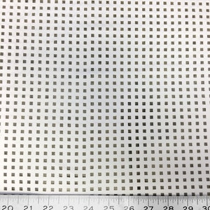 May include: A white sheet of paper with a grid pattern of small, evenly spaced squares. A metal ruler is placed at the bottom of the sheet, with the numbers 20 through 30 visible.
