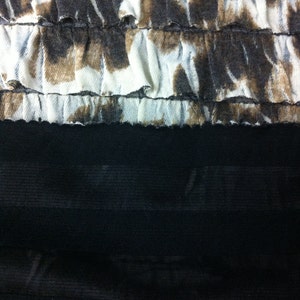 Peut inclure: Un tissu blanc avec un imprim&eacute; abstrait brun et blanc, avec un tissu noir en dessous. Le tissu blanc a un bord festonn&eacute;.