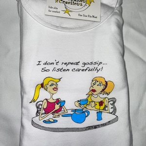 May include: White t-shirt with a cartoon illustration of two women sitting at a table with teacups and a teapot. The text "I don't repeat gossip... So listen carefully!" is printed on the shirt.