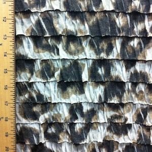 Peut inclure: Un gros plan sur un tissu blanc et brun avec une texture pliss&eacute;e. Le tissu pr&eacute;sente un motif de formes abstraites dans des tons de brun et de noir.