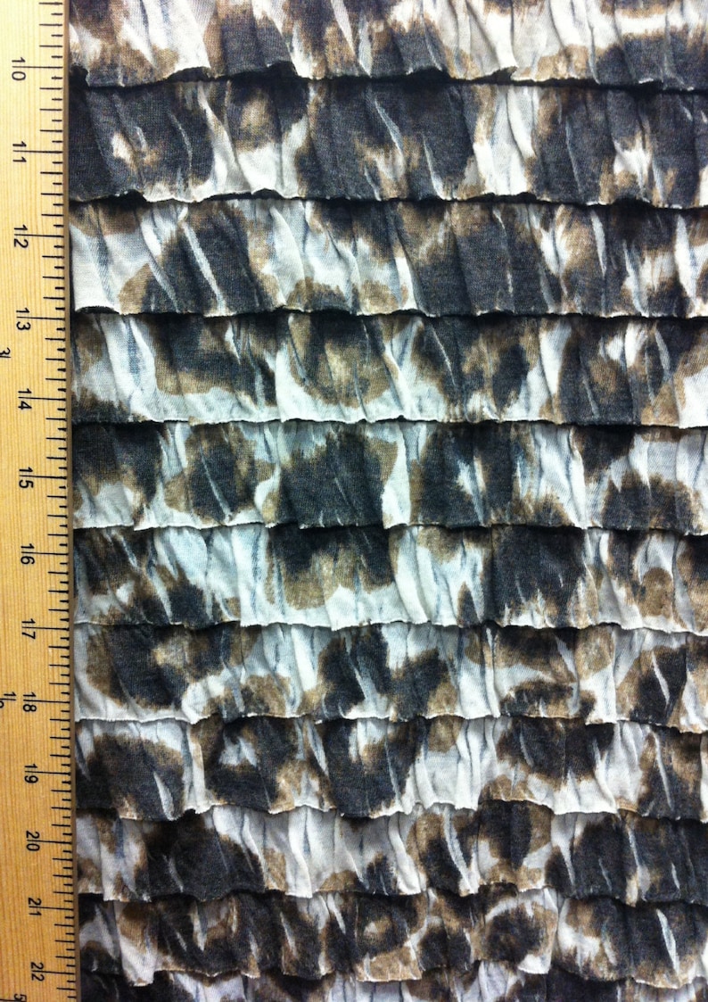 Peut inclure: Un gros plan sur un tissu blanc et brun avec une texture pliss&eacute;e. Le tissu pr&eacute;sente un motif de formes abstraites dans des tons de brun et de noir.