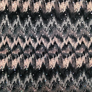 May include: Black fabric with a pink and silver chevron pattern. The fabric is covered in small, iridescent sequins.