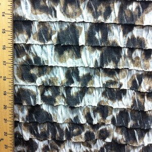 Peut inclure: Tissu blanc avec un imprim&eacute; abstrait brun et noir. Le tissu est rassembl&eacute; en volants.