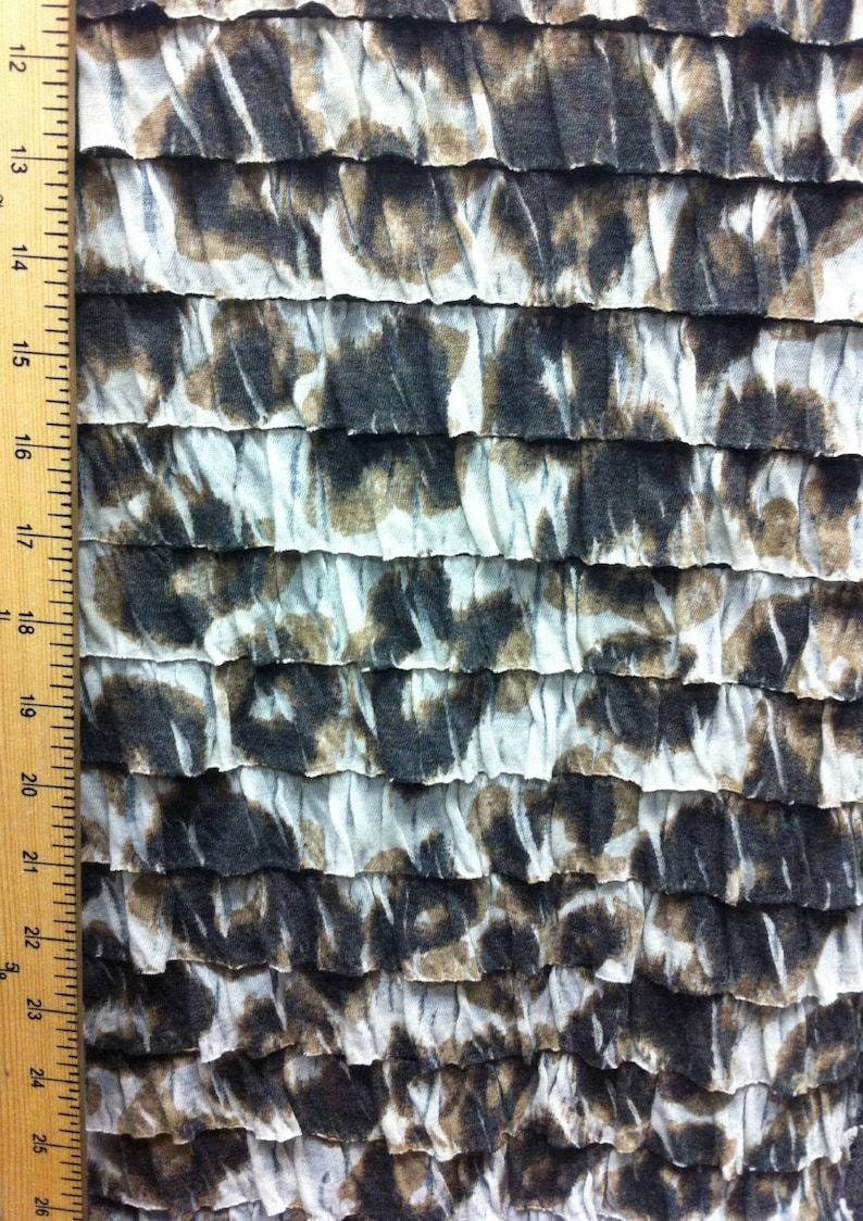 Peut inclure: Tissu blanc avec un imprim&eacute; abstrait brun et noir. Le tissu est rassembl&eacute; en volants.
