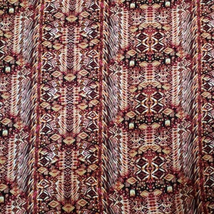 May include: A fabric with a repeating geometric pattern in shades of red, orange, and brown. The pattern is made up of diamonds, squares, and other shapes.