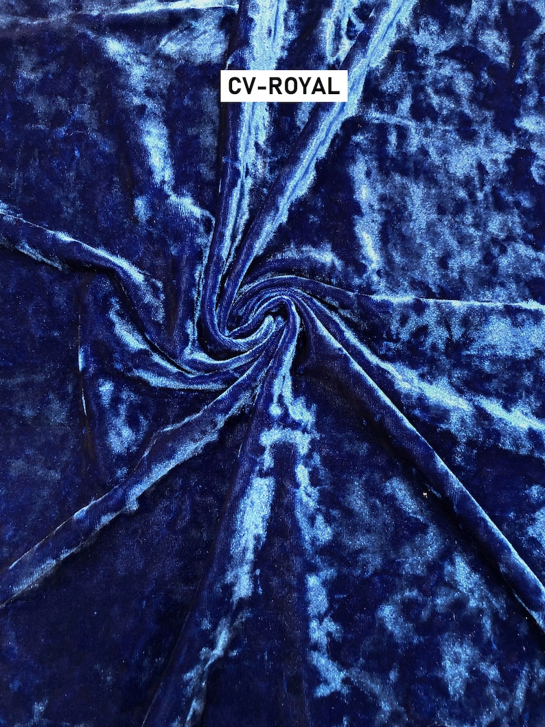 May include: Close-up of a deep blue crushed velvet fabric with a subtle shimmer. The fabric is folded and twisted, showing its texture. The text "CV-ROYAL" is printed in white on the fabric.