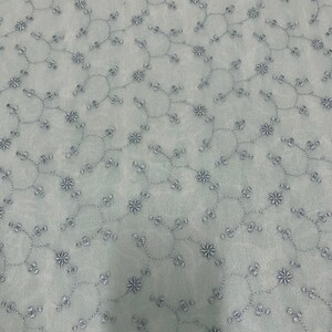 May include: A light blue fabric with a delicate pattern of embroidered silver flowers and vines.
