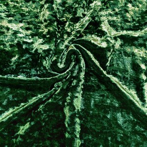 May include: Close-up of a hunter green crushed velvet fabric. The fabric has a textured, slightly shimmery surface.