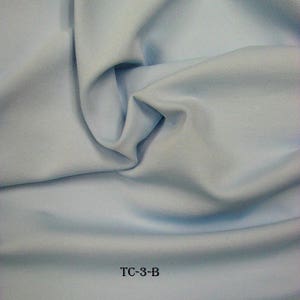 Puede incluir: Una muestra de tela azul claro con el texto "TC-3-B" impreso en ella.