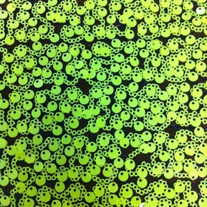 May include: A close-up of a fabric with a repeating pattern of lime green sequins. The sequins are arranged in a chain-like pattern.