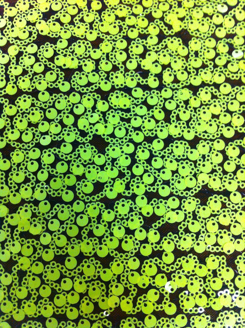 May include: A close-up of a fabric with a repeating pattern of lime green sequins. The sequins are arranged in a chain-like pattern.