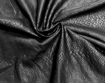 May include: Black faux leather fabric with a snakeskin pattern. The fabric is wrinkled and folded.