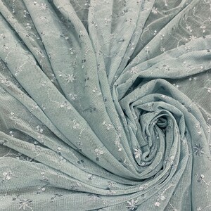 May include: A light blue sheer fabric with a delicate floral pattern. The fabric is soft and flowy, making it perfect for a variety of projects.
