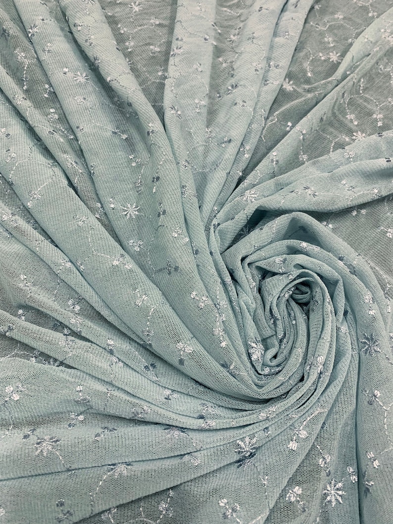 May include: A light blue sheer fabric with a delicate floral pattern. The fabric is soft and flowy, making it perfect for a variety of projects.
