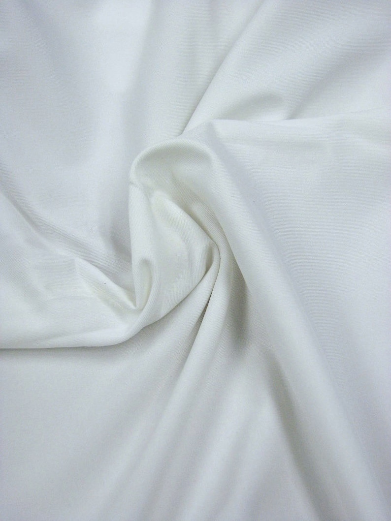 Puede incluir: Tela blanca con una textura suave y sedosa. La tela est&aacute; doblada y drapeada, mostrando su naturaleza suave y fluida.